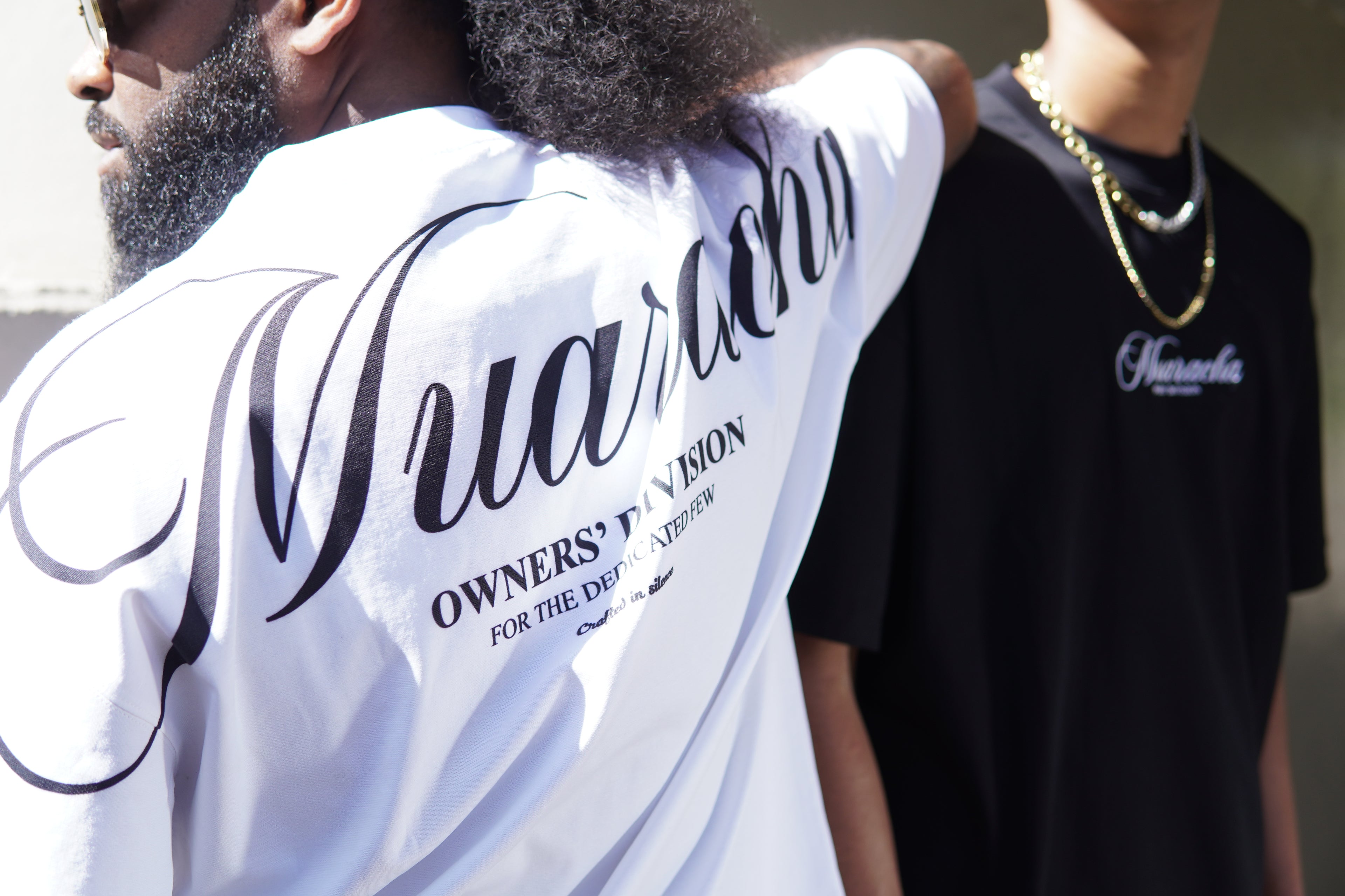 Person wearing a white shirt with 'Nua Racks' branding, standing next to another person in a black shirt with 'Nua Racks' logo.