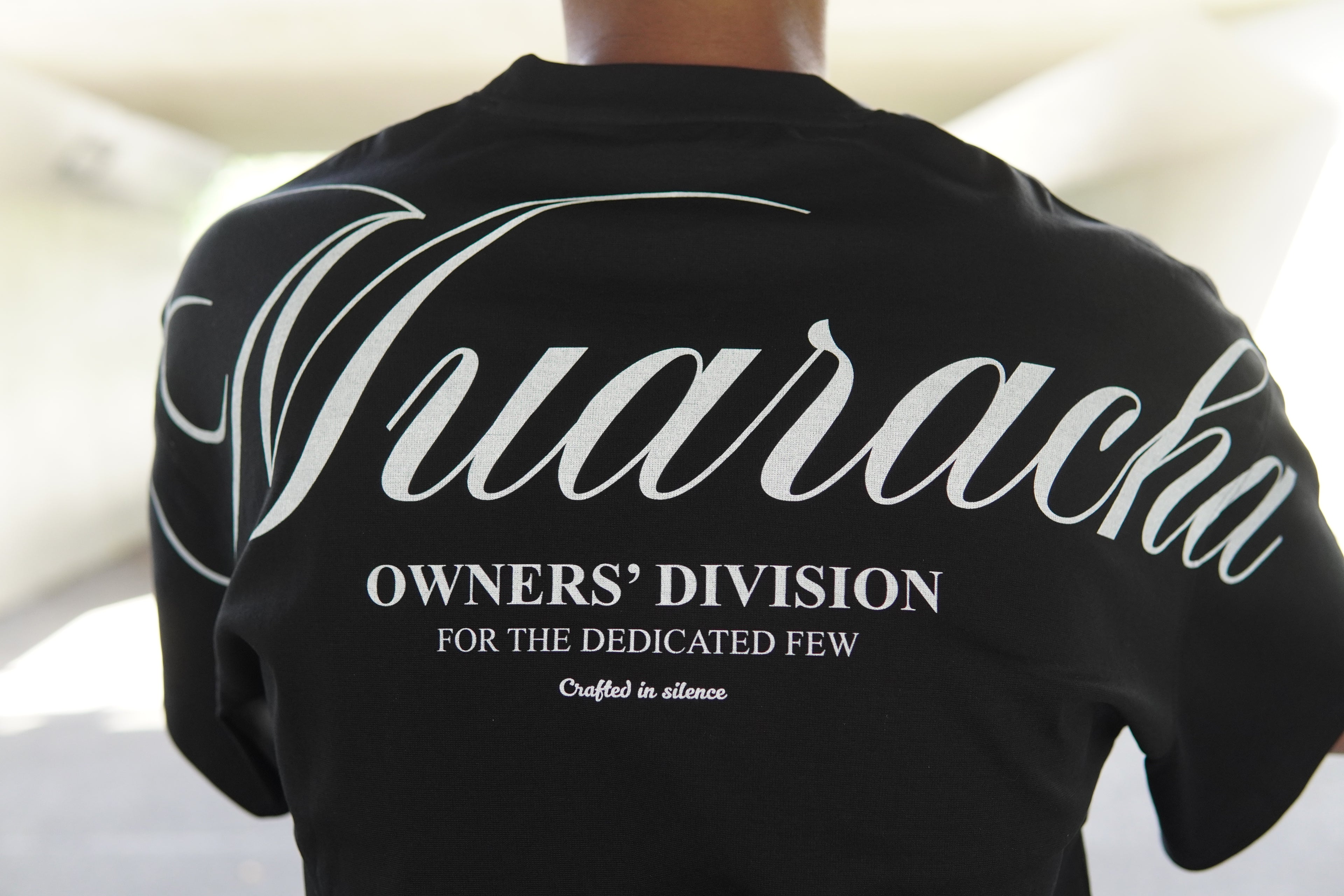 Black sweatshirt with 'Wuaracha' branding on a blurred background